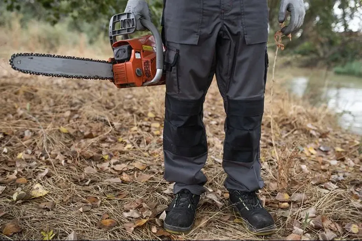 Professional lumberjack showing full chainsaw PPE including trousers, jacket and helmet