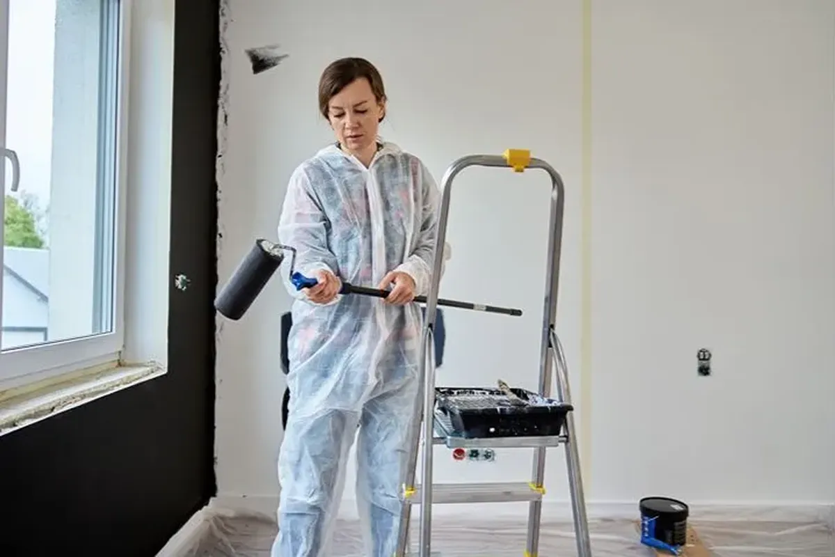 Painter in white coveralls using a roller on a wall